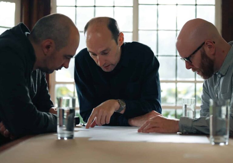 3 men sitting around a table